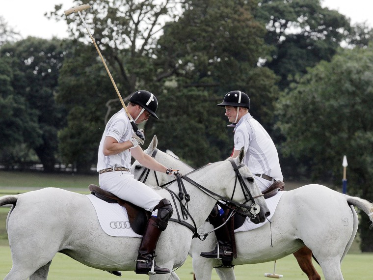 Image: Britain's Prince Harry speaks to Prince William during a charity polo match at Coworth Park, southern England